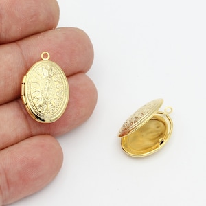 Op de afbeelding: Goudkleurige ovale locket met een ingewikkeld reliëf bloemenontwerp. Eén locket is gesloten, de andere is open en onthult de binnenkant. De locket heeft een kleine lus aan de bovenkant om aan een ketting te bevestigen. Sieradenaccessoire.