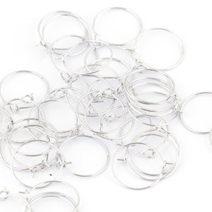 May include: A pile of silver hoop earrings, all of the same size and style.