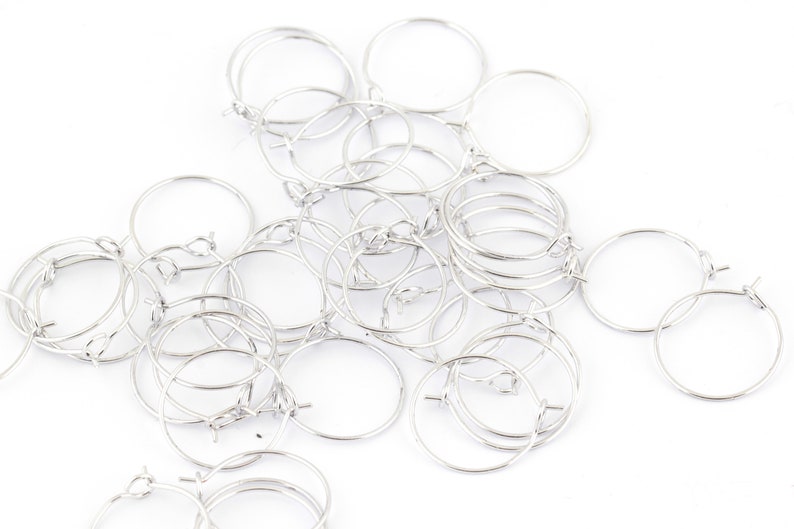 May include: A pile of silver hoop earrings, all of the same size and style.