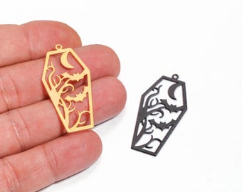 May include: Two coffin-shaped pendants with a Halloween theme. One is gold-colored, the other is black. Each pendant features a crescent moon, bats, and a tree design. The pendants have a small hole at the top for hanging.