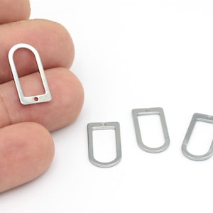 May include: Four silver metal oval-shaped charms with a hole at the top. The charms are about 1 inch long and 1/2 inch wide.
