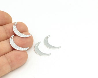 May include: Four silver crescent moon charms with a hammered texture. The charms have a hole at the top for attaching to jewelry.
