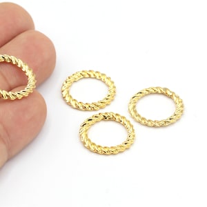 Puede incluir: Cuatro anillos de metal de color dorado con un diseño de cuerda trenzada. Los anillos tienen un diámetro de aproximadamente 2,5 cm.