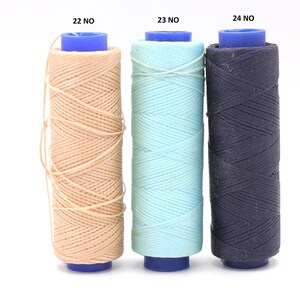 May include: Three spools of thread in different colours: beige, light blue, and dark blue. The spools are labelled 22 NO, 23 NO, and 24 NO.