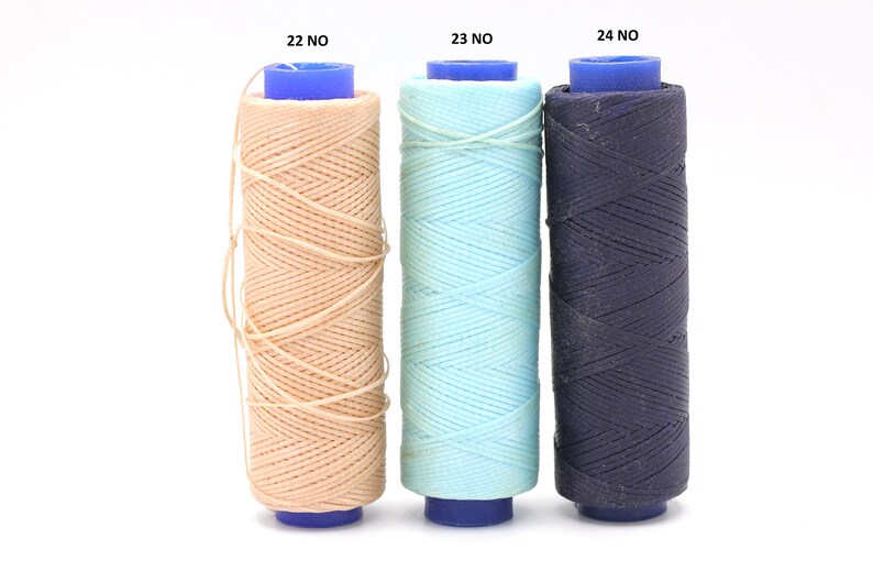 May include: Three spools of thread in different colours: beige, light blue, and dark blue. The spools are labelled 22 NO, 23 NO, and 24 NO.