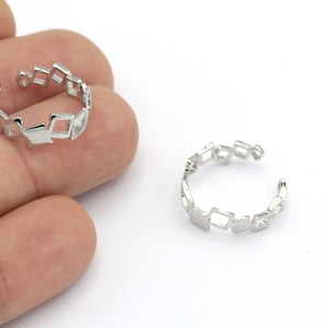 May include: Two silver rings with a geometric design. The rings are made of a series of connected squares.