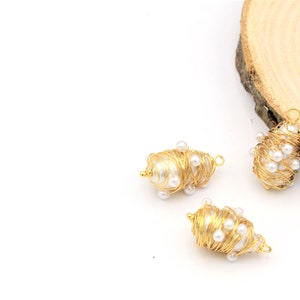 May include: Three gold wire wrapped pearl charms. Each charm is made of a single pearl wrapped in gold wire and decorated with smaller pearls.