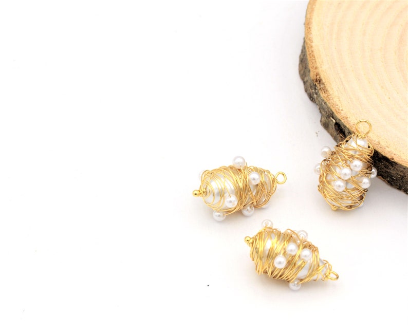 May include: Three gold wire wrapped pearl charms. Each charm is made of a single pearl wrapped in gold wire and decorated with smaller pearls.