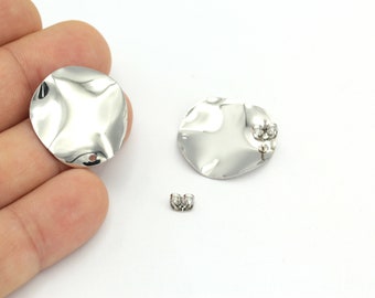 May include: Two silver metal earring blanks with a hammered texture. One blank has a small cluster of clear rhinestones. The blanks are shown on a white surface.