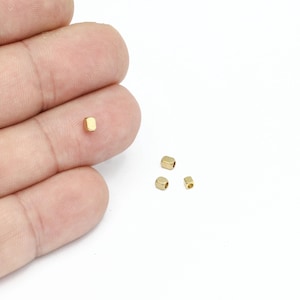 May include: Four small, gold-colored, square-shaped metal beads.