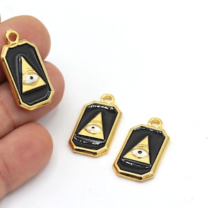 May include: Three gold-colored pendants with black enamel and a gold-colored eye inside a triangle. The pendants are shaped like rectangles with rounded corners.