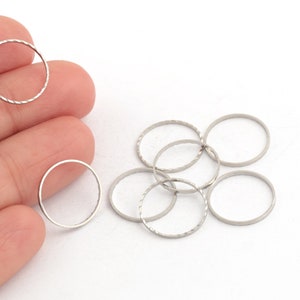 May include: A set of eight silver-toned metal jump rings. The rings are approximately 1 inch in diameter and have a textured surface.