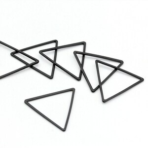 May include: Six black metal triangle shapes, some overlapping, on a white background. The triangles are all the same size and shape.