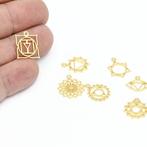May include: Seven gold-coloured metal charms with different designs, including a square, circles, and a flower. The charms are all about 2.5 cm in diameter and have a hole at the top for attaching to a chain or bracelet.