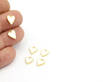 May include: Five gold-coloured heart-shaped charms with white enamel. The charms have a small loop at the top for attaching to jewellery or other crafts.