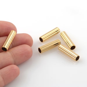 Op de afbeelding: Vijf gouden metalen eindkappen voor koorden of het maken van sieraden. De eindkappen hebben een geribbelde textuur.