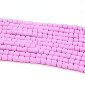 May include: A strand of light pink matte finish round beads. The beads are arranged in rows and are uniform in size and shape.