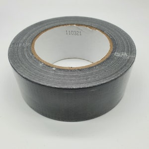 K&ouml;nnte beinhalten: Eine Rolle graues Panzerband mit einem wei&szlig;en Innenkern. Das Klebeband hat eine einfarbige graue Farbe und eine strukturierte Oberfl&auml;che. Die Nummer "110321" ist auf dem Innenkern aufgedruckt.