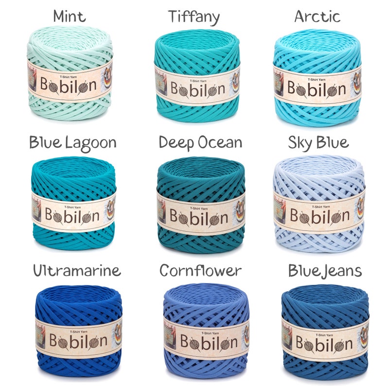 May include: Nine spools of T-shirt yarn in various shades of blue and green, labeled with names like "Mint," "Tiffany," and "Blue Lagoon." Each spool has a "Bobilon" label. The yarn is tightly wound, showcasing the texture and color variations.