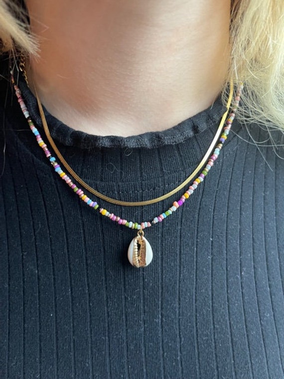 Necklace decorated with small golden beads and colors with a shell