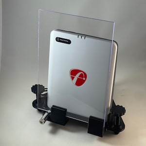 May include: A white device with a red logo and the text "Fusion Tracking" is held in place by a black mounting system with adjustable knobs. A clear plastic shield is in front of the device. The device is on a white surface.