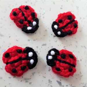 May include: Four crocheted red ladybirds with black spots and white accents.