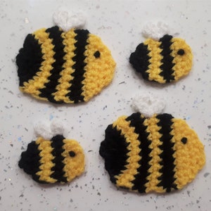 May include: Four crocheted bumblebees in different sizes. The bees are yellow and black with white wings.