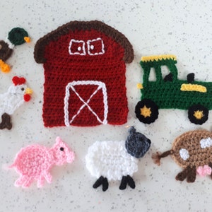 May include: A set of crocheted farm animal toys, including a red barn, a green tractor, a white chicken, a pink pig, a white sheep, a brown cow, and a brown duck.