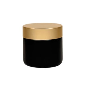 Op de afbeelding: Een zwarte pot met een gouden deksel. De pot is cilindrisch met een gladde, matte afwerking. Het deksel is een platte, cirkelvormige schijf met een glanzende, metallic gouden kleur. De pot wordt waarschijnlijk gebruikt voor het bewaren van cosmetica of andere kleine items.