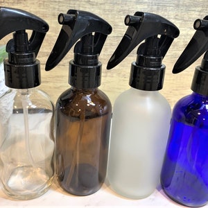 May include: Four glass spray bottles with black trigger sprayers. The bottles are clear, amber, frosted, and blue.
