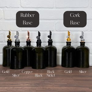 Pu&ograve; includere: Otto bottiglie di vetro con tappi di diversi colori, tra cui oro, argento, rame, nero e nichel. Le bottiglie sono disposte in due file da quattro, con il testo "Rubber Base" e "Cork Base" sopra ogni fila. Le bottiglie sono su una superficie di legno.