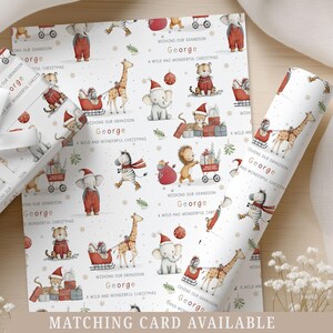 K&ouml;nnte beinhalten: Weihnachtliches Geschenkpapier mit Illustrationen von Tieren mit Weihnachtsm&uuml;tzen. Der Text lautet: &bdquo;Wishing our Grandson George, A Wild and Wonderful Christmas.&ldquo; Eine passende Karte ist erh&auml;ltlich.