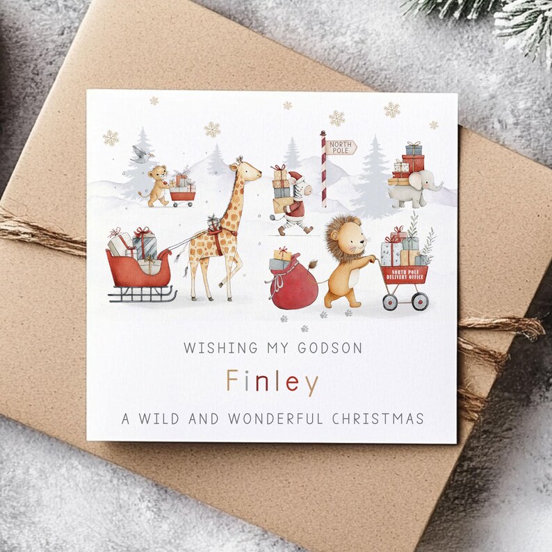 K&ouml;nnte beinhalten: Weihnachtskarte mit einer Winterszene mit Zeichentricktieren. Eine Giraffe zieht einen Schlitten, ein L&ouml;we schiebt einen Wagen und ein Elefant tr&auml;gt Geschenke. Auf der Karte steht: "Wishing My Godson Finley A Wild and Wonderful Christmas".