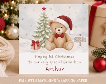May include: A square greeting card featuring a watercolor illustration of a brown teddy bear wearing a red Santa hat and a red bow tie, sitting next to a Christmas tree, a gift, and a sign that reads 2026. The text reads Happy 1st Christmas to our very special Grandson Arthur.