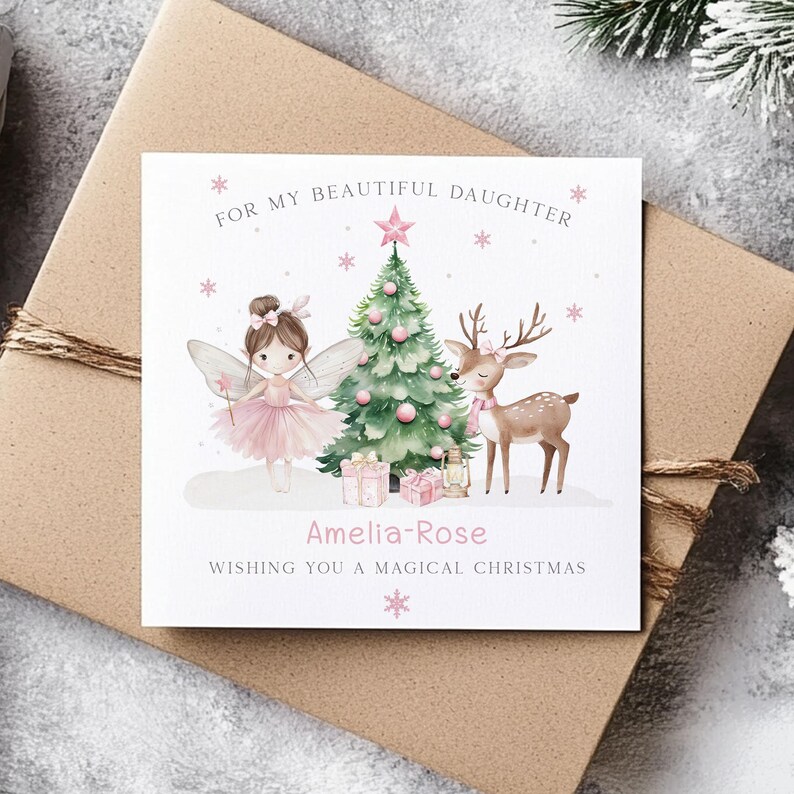 May include: A Christmas card with a fairy, a deer, and a Christmas tree. The card is decorated with pink accents and the text "For my beautiful daughter" and "Wishing you a magical Christmas". The name "Amelia-Rose" is also on the card.