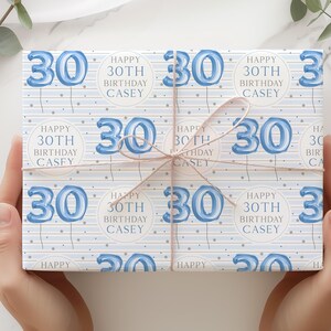 May include: Blue and white wrapping paper with a repeating pattern of blue number 30 balloons and the text "Happy 30th Birthday Casey".
