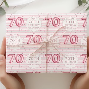 May include: Pink wrapping paper with a repeating pattern of the number 70 in a balloon style, the text "Happy 70th Birthday Grandma", hearts, and stars. The wrapped gift is tied with twine.