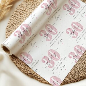 May include: White wrapping paper with a pink floral pattern and the text "Happy 30th Birthday to a Very Special Friend" repeated throughout. The number "30" is written in a large, cursive font with pink floral accents.
