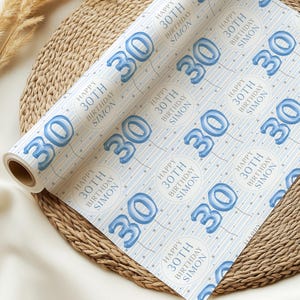 May include: Blue and white wrapping paper with a repeating pattern of blue balloons in the shape of the number 30. The balloons have a white outline and are surrounded by white stars. The text "Happy 30th Birthday Simon" is repeated throughout the pattern.