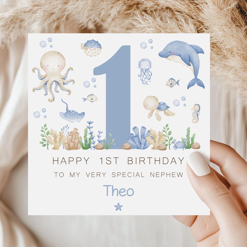 Puede incluir: Tarjeta de cumplea&ntilde;os cuadrada con un n&uacute;mero 1 azul y ilustraciones marinas. El texto dice: "Happy 1st Birthday To My Very Special Nephew Theo". El dise&ntilde;o presenta ilustraciones de acuarela de animales marinos y plantas.