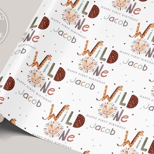 K&ouml;nnte beinhalten: Wei&szlig;es Geschenkpapier mit einem sich wiederholenden Muster aus einer Giraffe und einem L&ouml;wen mit den Worten "Wild One" und "Happy First Birthday Jacob".