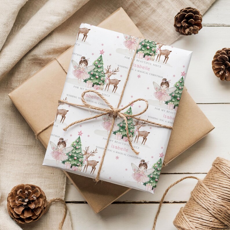 May include: Wrapped gift with a festive Christmas theme. The white wrapping paper features illustrations of fairies, deer, and Christmas trees. The text reads "For my beautiful niece Isabelle, wishing you a magical Christmas." Tied with twine.