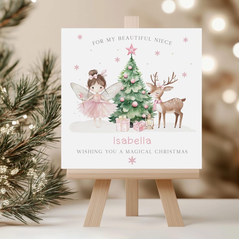 May include: A Christmas card on a wooden easel features a fairy, a decorated tree, and a reindeer. The card has the text "For my beautiful niece" and "Wishing you a magical Christmas". The name "Isabella" is also on the card.