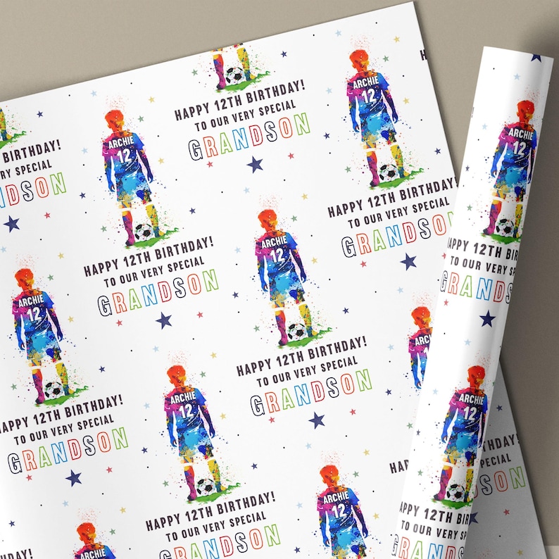 May include: White wrapping paper featuring a repeating pattern of a soccer player in a blue and orange uniform. The text reads "Happy 12th Birthday! To our very special Grandson" with colorful stars.