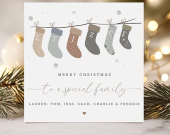 May include: A Christmas card with six stockings hanging from a string, each with a different letter. The card reads "Merry Christmas to a special family" with names below. The stockings are in shades of brown, gray, and blue.