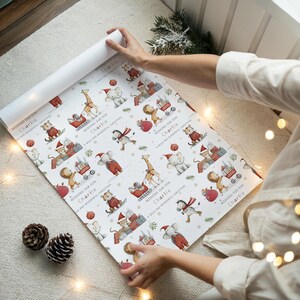 K&ouml;nnte beinhalten: Wei&szlig;es Weihnachtspapier mit einem sich wiederholenden Muster von Cartoon-Tieren in Weihnachtsm&uuml;tzen. Der Text "Wishing our son Charlie, A wild and wonderful Christmas" ist auf dem Papier aufgedruckt.