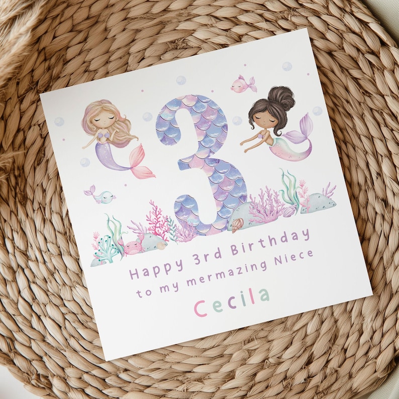 May include: A white card with a purple and blue mermaid tail number 3, two mermaids, and the text "Happy 3rd Birthday to my mermazing Niece Cecila".