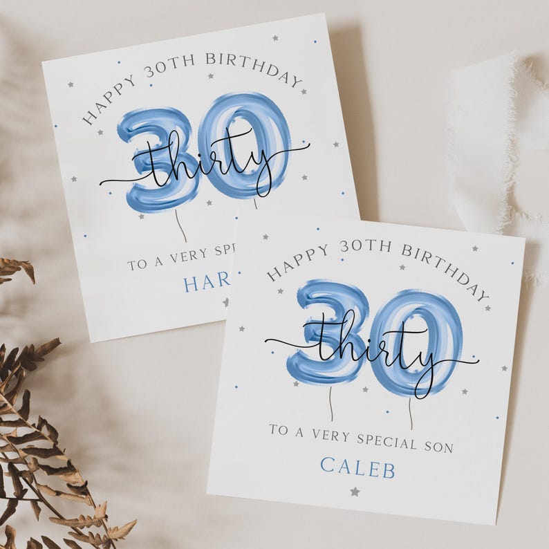 May include: Two white greeting cards with blue and silver accents. The cards feature the number 30 in blue with the word "thirty" written in black script. The text on the cards reads "Happy 30th Birthday" and "To a very special [name]"