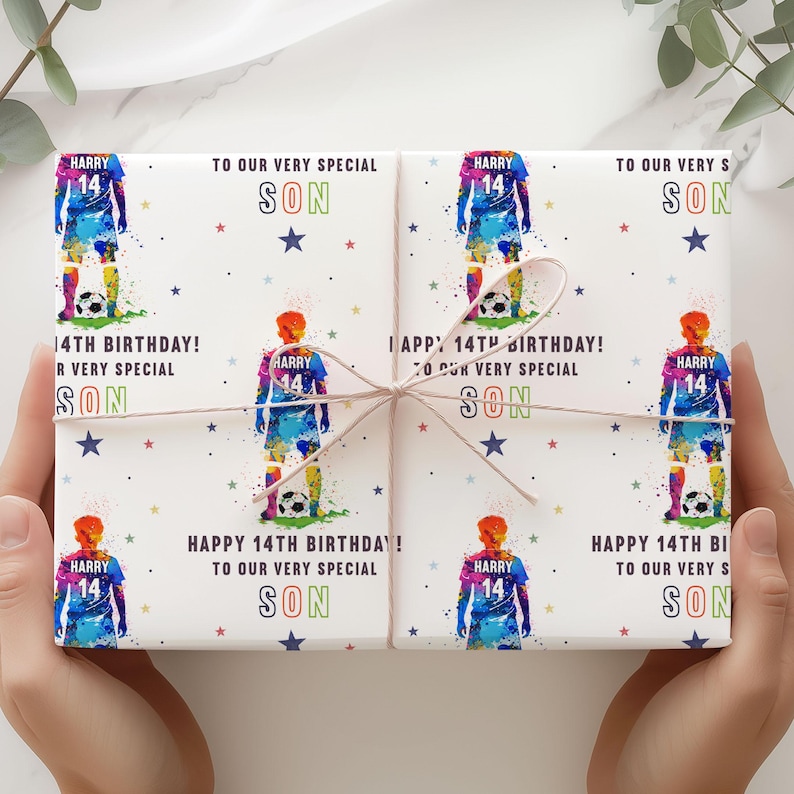 May include: White wrapping paper with a colorful soccer player design. The paper has the text "Happy 14th Birthday! To our very special son" repeated on each side.