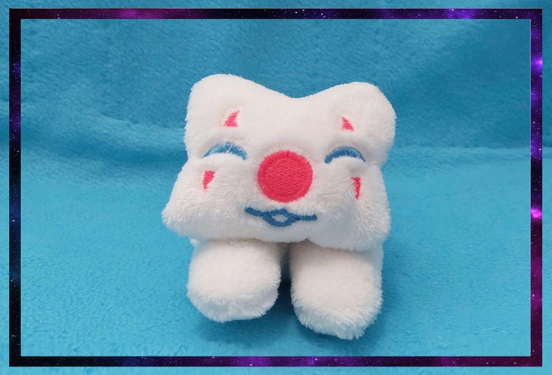 May include: A white plush toy with a smiling face, featuring a pink nose, blue eyes, and red accents. The toy has a star-like shape and two small feet. The background is a light blue fabric with a purple and black border.